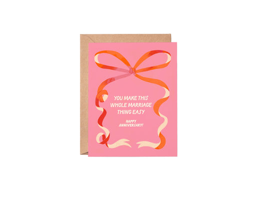 Pink card with orange bow and anniversary message on a white background