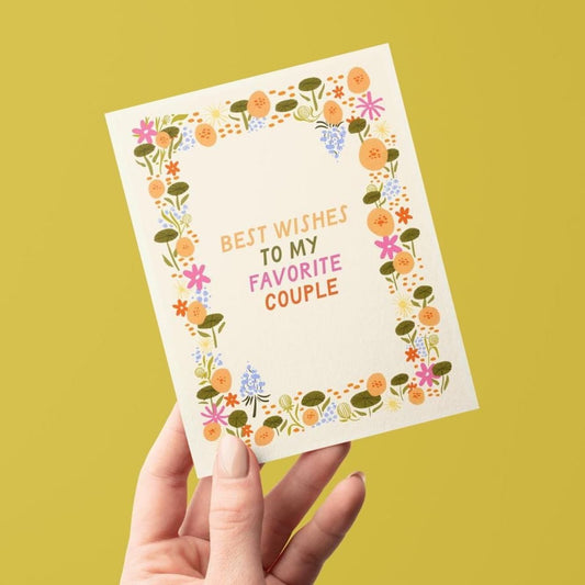 Hand holding a card with floral design and text on a yellow background